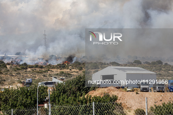 Smoke is being seen behind an industrial building in Limassol, Cyprus, on May 31, 2024. Some buildings are being endangered after a fire bre...