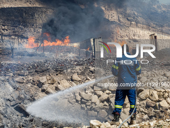 A firefighter is trying to put out the fire in Limassol, Cyprus, on May 31, 2024. Some buildings are in danger after a fire breaks out in th...