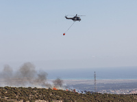 A helicopter is flying above the flames in Limassol, Cyprus, on May 31, 2024. Some buildings are in danger after a fire breaks out in the Ag...