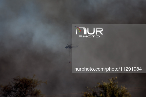 A helicopter is being seen through the smoke in Limassol, Cyprus, on May 31, 2024. Some buildings are in danger after a fire breaks out in t...