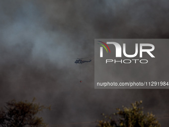 A helicopter is being seen through the smoke in Limassol, Cyprus, on May 31, 2024. Some buildings are in danger after a fire breaks out in t...