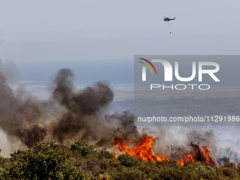 A helicopter is flying above the flames in Limassol, Cyprus, on May 31, 2024. Some buildings are in danger after a fire breaks out in the Ag...