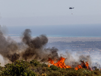 A helicopter is flying above the flames in Limassol, Cyprus, on May 31, 2024. Some buildings are in danger after a fire breaks out in the Ag...