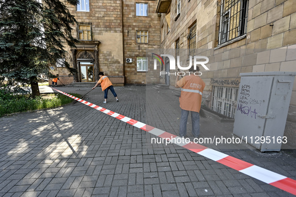 Municipal workers are sweeping away debris outside a residential building after the Russian missile attack in Zaporizhzhia, Ukraine, on June...