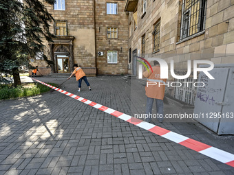 Municipal workers are sweeping away debris outside a residential building after the Russian missile attack in Zaporizhzhia, Ukraine, on June...