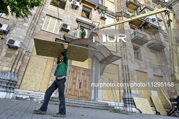 A municipal worker is carrying a particle board to seal a smashed window at a residential building damaged by the Russian missile attack in...