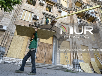 A municipal worker is carrying a particle board to seal a smashed window at a residential building damaged by the Russian missile attack in...