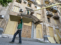 A municipal worker is carrying a particle board to seal a smashed window at a residential building damaged by the Russian missile attack in...