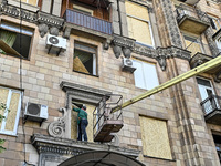 A municipal worker is using an aerial work platform to seal a smashed window with a particle board at a residential building damaged by the...