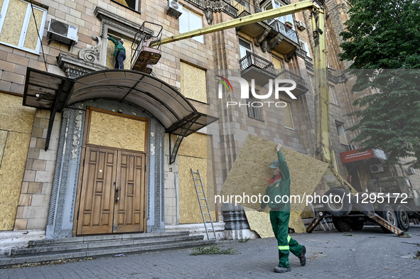 A municipal worker is carrying a particle board to seal a smashed window at a residential building damaged by the Russian missile attack in...