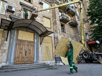 A municipal worker is carrying a particle board to seal a smashed window at a residential building damaged by the Russian missile attack in...