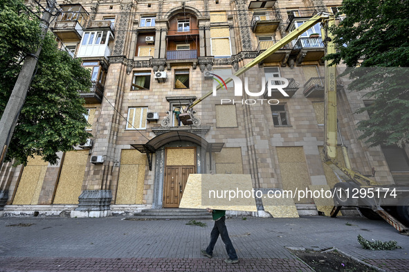 A municipal worker is carrying a particle board to seal a smashed window at a residential building damaged by the Russian missile attack in...