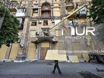 A municipal worker is carrying a particle board to seal a smashed window at a residential building damaged by the Russian missile attack in...