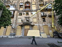 A municipal worker is carrying a particle board to seal a smashed window at a residential building damaged by the Russian missile attack in...