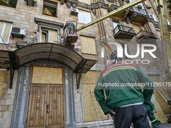 A municipal worker is using an aerial work platform to seal a smashed window with a particle board at a residential building damaged by the...