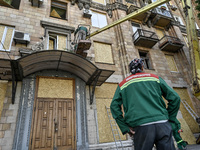 A municipal worker is using an aerial work platform to seal a smashed window with a particle board at a residential building damaged by the...