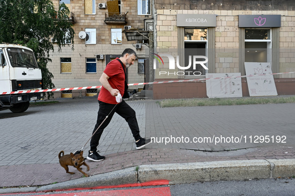 A man is walking a dog past a residential building damaged by the Russian missile attack in Zaporizhzhia, Ukraine, on June 1, 2024. In Zapor...