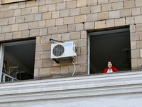 An elderly woman is looking out of a smashed window in a residential building after the Russian missile attack in Zaporizhzhia, Ukraine, on...