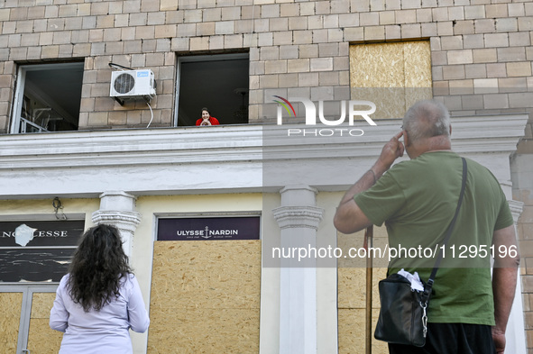 An elderly woman is looking out of a smashed window in a residential building after the Russian missile attack in Zaporizhzhia, Ukraine, on...