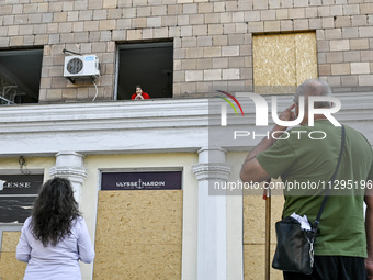 An elderly woman is looking out of a smashed window in a residential building after the Russian missile attack in Zaporizhzhia, Ukraine, on...