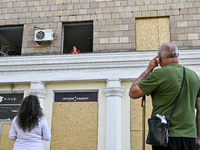 An elderly woman is looking out of a smashed window in a residential building after the Russian missile attack in Zaporizhzhia, Ukraine, on...