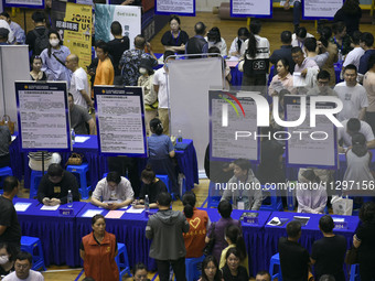 Job seekers are looking for a suitable position at a job fair held by industrial reform enterprises in Huai'an, China, on June 2, 2024. (