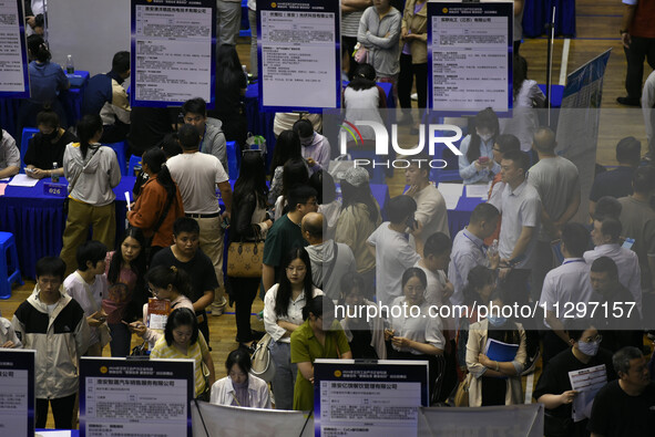 Job seekers are looking for a suitable position at a job fair held by industrial reform enterprises in Huai'an, China, on June 2, 2024. 