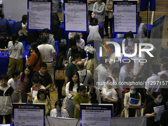 Job seekers are looking for a suitable position at a job fair held by industrial reform enterprises in Huai'an, China, on June 2, 2024. (