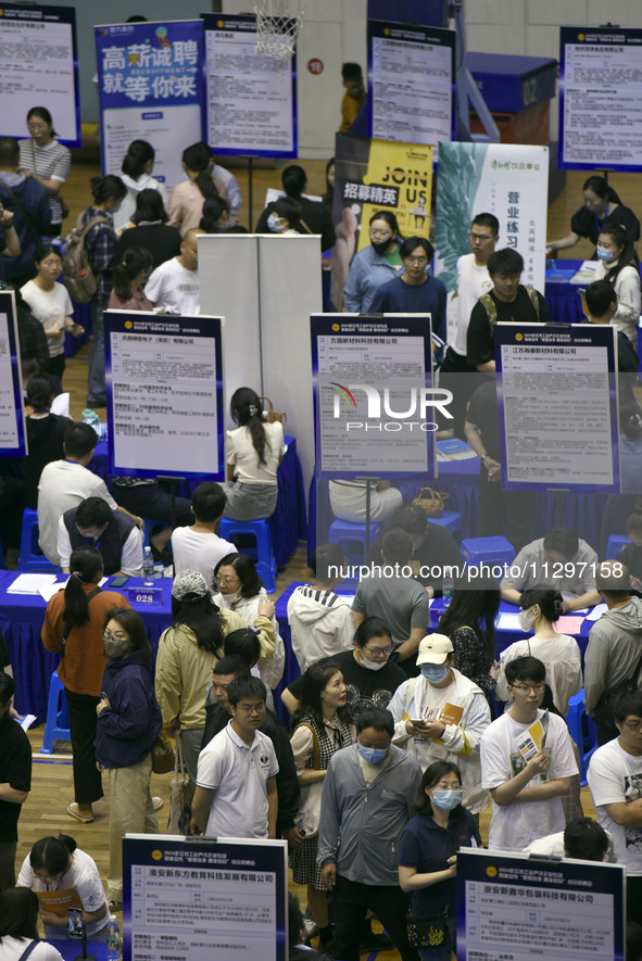 Job seekers are looking for a suitable position at a job fair held by industrial reform enterprises in Huai'an, China, on June 2, 2024. 