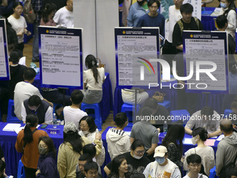 Job seekers are looking for a suitable position at a job fair held by industrial reform enterprises in Huai'an, China, on June 2, 2024. (