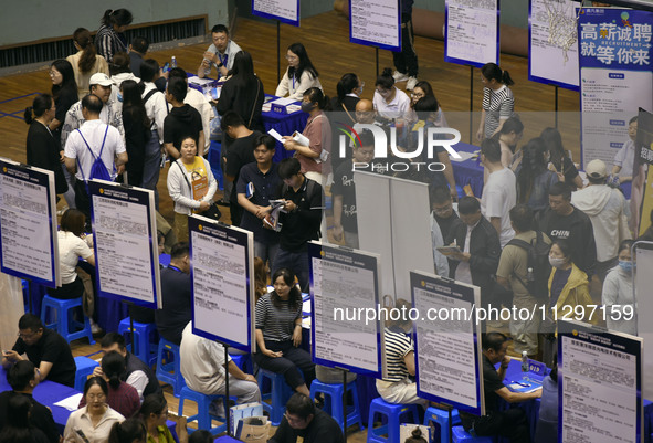 Job seekers are looking for a suitable position at a job fair held by industrial reform enterprises in Huai'an, China, on June 2, 2024. 