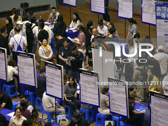 Job seekers are looking for a suitable position at a job fair held by industrial reform enterprises in Huai'an, China, on June 2, 2024. (