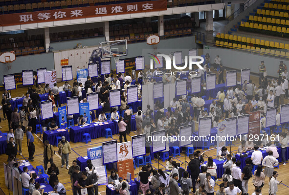 Job seekers are looking for a suitable position at a job fair held by industrial reform enterprises in Huai'an, China, on June 2, 2024. 