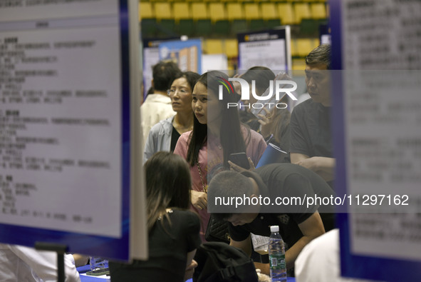 Job seekers are looking for a suitable position at a job fair held by industrial reform enterprises in Huai'an, China, on June 2, 2024. 