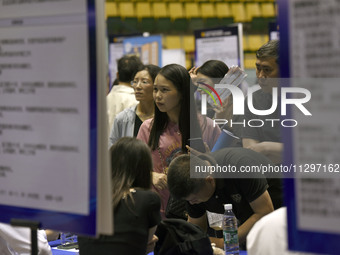 Job seekers are looking for a suitable position at a job fair held by industrial reform enterprises in Huai'an, China, on June 2, 2024. (