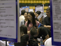 Job seekers are looking for a suitable position at a job fair held by industrial reform enterprises in Huai'an, China, on June 2, 2024. (