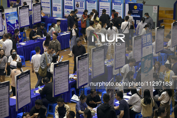 Job seekers are looking for a suitable position at a job fair held by industrial reform enterprises in Huai'an, China, on June 2, 2024. 