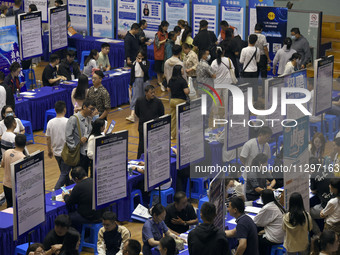 Job seekers are looking for a suitable position at a job fair held by industrial reform enterprises in Huai'an, China, on June 2, 2024. (