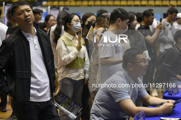 Job seekers are looking for a suitable position at a job fair held by industrial reform enterprises in Huai'an, China, on June 2, 2024. 