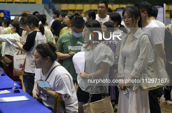 Job seekers are looking for a suitable position at a job fair held by industrial reform enterprises in Huai'an, China, on June 2, 2024. 