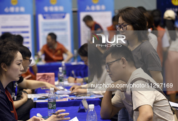 Job seekers are looking for a suitable position at a job fair held by industrial reform enterprises in Huai'an, China, on June 2, 2024. 