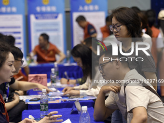 Job seekers are looking for a suitable position at a job fair held by industrial reform enterprises in Huai'an, China, on June 2, 2024. (