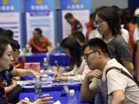 Job seekers are looking for a suitable position at a job fair held by industrial reform enterprises in Huai'an, China, on June 2, 2024. (