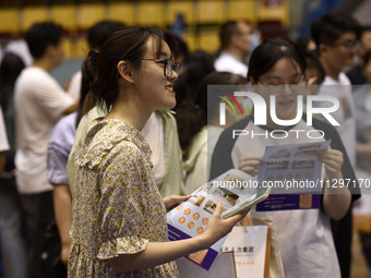 Job seekers are looking for a suitable position at a job fair held by industrial reform enterprises in Huai'an, China, on June 2, 2024. (