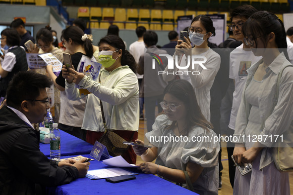 Job seekers are looking for a suitable position at a job fair held by industrial reform enterprises in Huai'an, China, on June 2, 2024. 