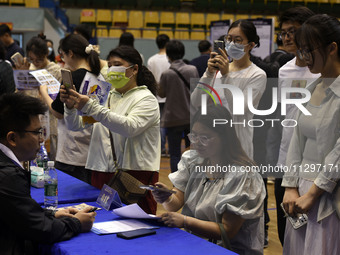 Job seekers are looking for a suitable position at a job fair held by industrial reform enterprises in Huai'an, China, on June 2, 2024. (