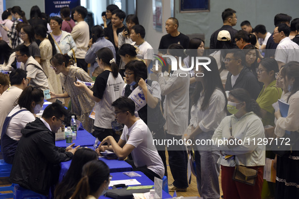 Job seekers are looking for a suitable position at a job fair held by industrial reform enterprises in Huai'an, China, on June 2, 2024. 