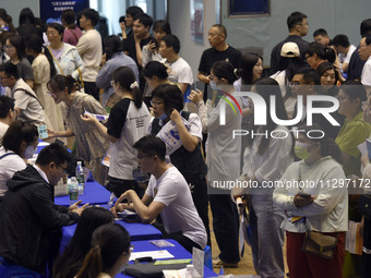 Job seekers are looking for a suitable position at a job fair held by industrial reform enterprises in Huai'an, China, on June 2, 2024. (