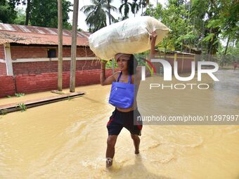 A man is carrying his belongings as he is walking through a flooded road in the aftermath of Cyclone Remal, in Nagaon district of Assam, Ind...