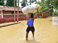 A man is carrying his belongings as he is walking through a flooded road in the aftermath of Cyclone Remal, in Nagaon district of Assam, Ind...